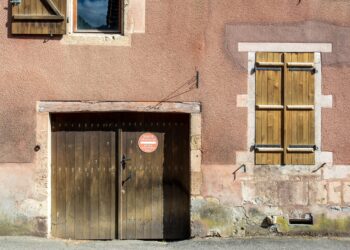 Charming old building facade with rustic wooden doors and shutters in urban setting.