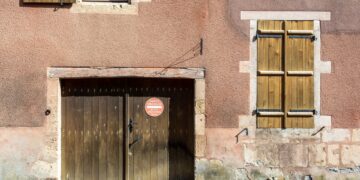 Charming old building facade with rustic wooden doors and shutters in urban setting.