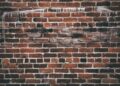 A close-up of a red brick wall with white paint drippings, offering a textured urban background.