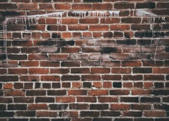 A close-up of a red brick wall with white paint drippings, offering a textured urban background.