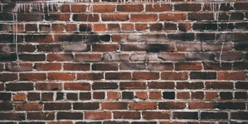 A close-up of a red brick wall with white paint drippings, offering a textured urban background.
