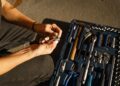 Close-up of hands using tools from a toolset in a well-lit workshop setting.