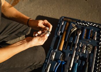 Close-up of hands using tools from a toolset in a well-lit workshop setting.
