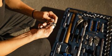 Close-up of hands using tools from a toolset in a well-lit workshop setting.