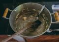 Aerial view of a cooking pot with leftover dough and utensils, highlighting kitchen preparation.