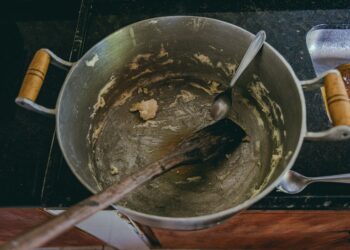 Aerial view of a cooking pot with leftover dough and utensils, highlighting kitchen preparation.