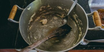 Aerial view of a cooking pot with leftover dough and utensils, highlighting kitchen preparation.