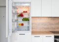 Contemporary kitchen with refrigerator filled with fresh bright tomatoes lettuce and bell peppers