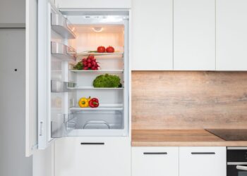 Contemporary kitchen with refrigerator filled with fresh bright tomatoes lettuce and bell peppers