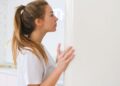 Woman looking into a white fridge in a modern domestic kitchen setting.