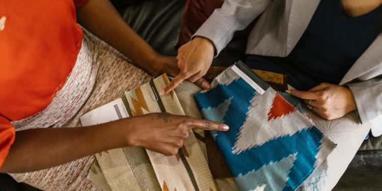 Two professionals assessing colorful fabric swatches for interior design project.