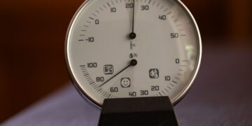 Close-up of an analog hygrometer and thermometer displaying temperature and humidity indoors.