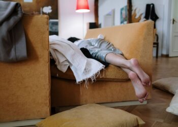 A person relaxing barefoot on a cozy sofa indoors, enjoying a peaceful moment.