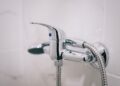 A detailed view of a sleek chrome shower faucet in a clean bathroom setting.