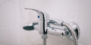 A detailed view of a sleek chrome shower faucet in a clean bathroom setting.