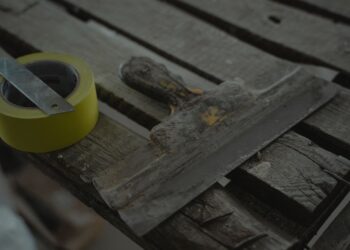 Close-up of a spatula and duct tape on an aged wooden surface. Perfect for DIY and renovation themes.