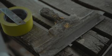 Close-up of a spatula and duct tape on an aged wooden surface. Perfect for DIY and renovation themes.