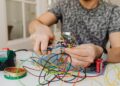 Person using pliers to cut through colorful electrical wires, showcasing DIY electronics work.