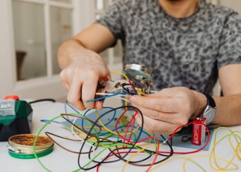 Person using pliers to cut through colorful electrical wires, showcasing DIY electronics work.