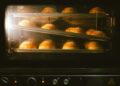 Golden brown bread rolls baking in an oven, showcasing warmth and homey ambience.