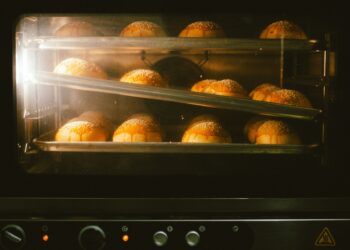 Golden brown bread rolls baking in an oven, showcasing warmth and homey ambience.