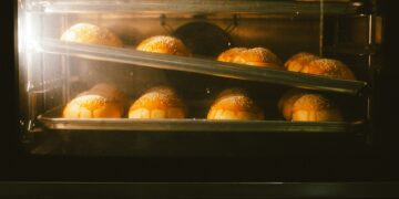 Golden brown bread rolls baking in an oven, showcasing warmth and homey ambience.
