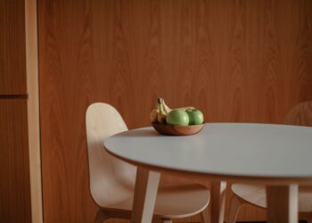 A simple fruit bowl with green apples and bananas on a sleek wooden table, perfect for a modern kitchen.
