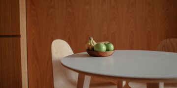 A simple fruit bowl with green apples and bananas on a sleek wooden table, perfect for a modern kitchen.