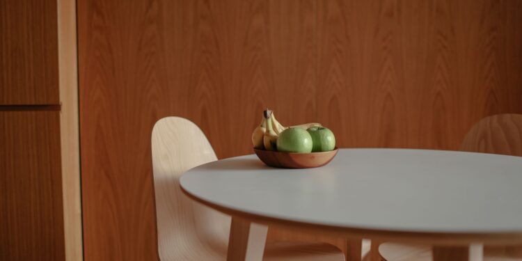 A simple fruit bowl with green apples and bananas on a sleek wooden table, perfect for a modern kitchen.