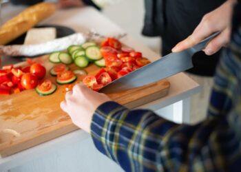 Cutting fresh vegetables for a healthy salad, showcasing tomatoes, cucumbers, and peppers.