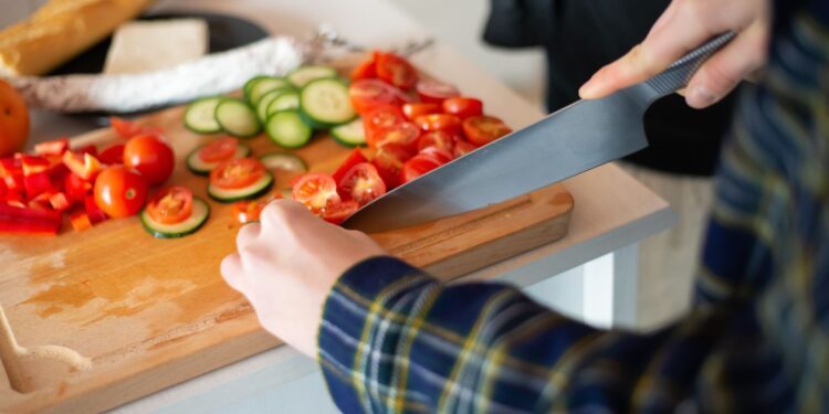 Cutting fresh vegetables for a healthy salad, showcasing tomatoes, cucumbers, and peppers.