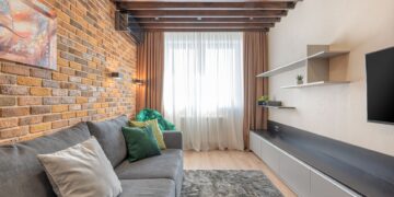 Stylish living room interior featuring a rustic brick wall, comfortable gray sofa, and elegant decor.