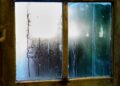 Close-up of a moist wooden window pane with condensation creating artistic streaks in Leiden, Netherlands.