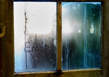 Close-up of a moist wooden window pane with condensation creating artistic streaks in Leiden, Netherlands.