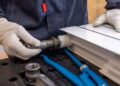 Close-up of a plumber installing a radiator pipe using specialized tools.