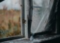 Old window frame with peeling paint, showcasing a charming rustic look with clear glass view.