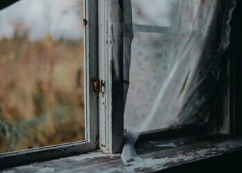 Old window frame with peeling paint, showcasing a charming rustic look with clear glass view.