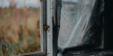 Old window frame with peeling paint, showcasing a charming rustic look with clear glass view.