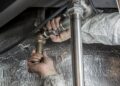 Close-up of a plumber's hands installing steel pipes indoors, showcasing skilled manual work.
