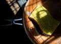 A yellow sponge rests in a copper pan, lit by dramatic shadows. Ideal for cleaning themes.
