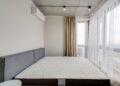 Spacious modern bedroom with a clean mattress and large windows for natural light.