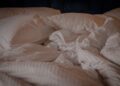 A comfortable and inviting bed with white pillows and a crumpled duvet, perfect for a relaxing setting.