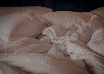 A comfortable and inviting bed with white pillows and a crumpled duvet, perfect for a relaxing setting.