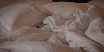 A comfortable and inviting bed with white pillows and a crumpled duvet, perfect for a relaxing setting.