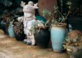 Cute winter-themed statue with potted plants on a rustic stone surface.