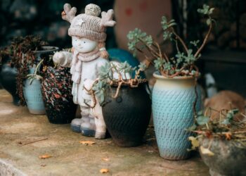 Cute winter-themed statue with potted plants on a rustic stone surface.