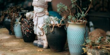 Cute winter-themed statue with potted plants on a rustic stone surface.