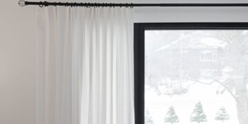 White curtains partially covering a window with a snowy outdoor view. Minimalist home decor.