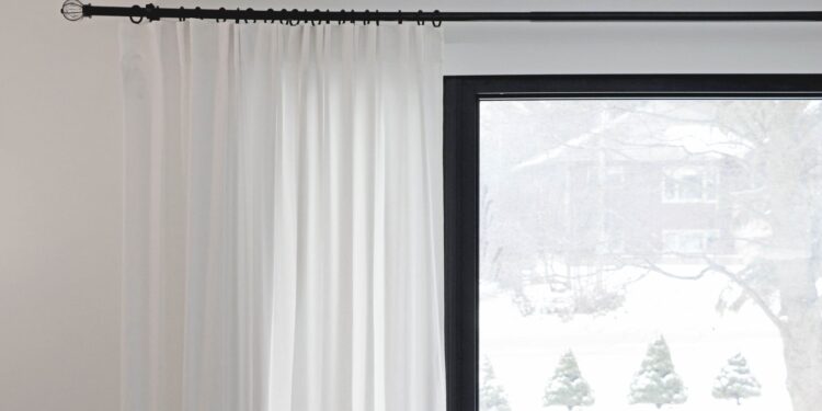 White curtains partially covering a window with a snowy outdoor view. Minimalist home decor.