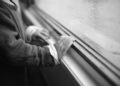 A child's hand touching a rainy window, expressing curiosity and solitude.